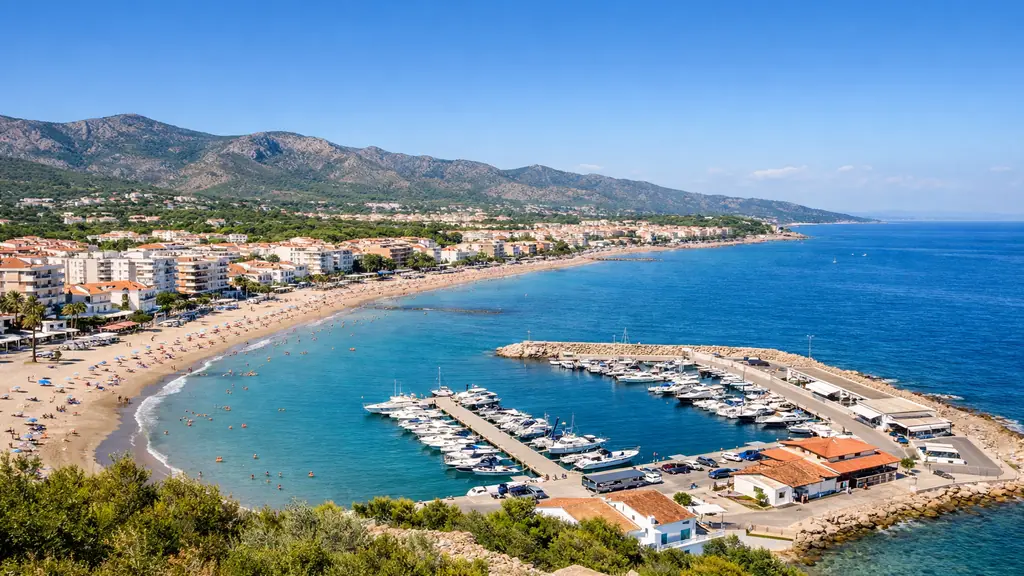 Vue réaliste d’Alcossebre sur la Costa del Azahar avec plage de sable, petit port de plaisance, mer turquoise et reliefs de la Sierra de Irta en arrière-plan