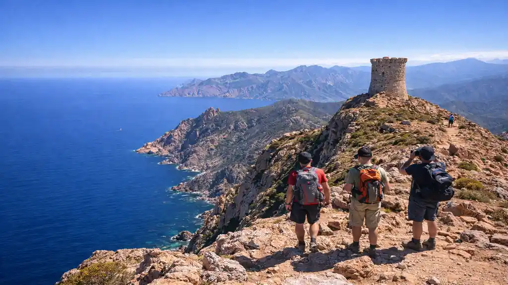 Randonnée à Capo Rosso en Corse avec la tour génoise, falaises rouges et panorama sur la Méditerranée depuis un sentier de crête.
