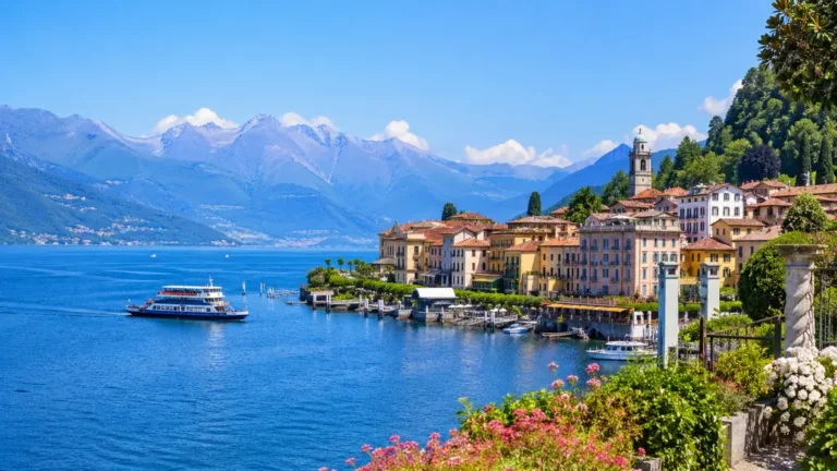 Lacs italiens du Nord avec village au bord de l’eau, bateau, montagnes et paysage lumineux.