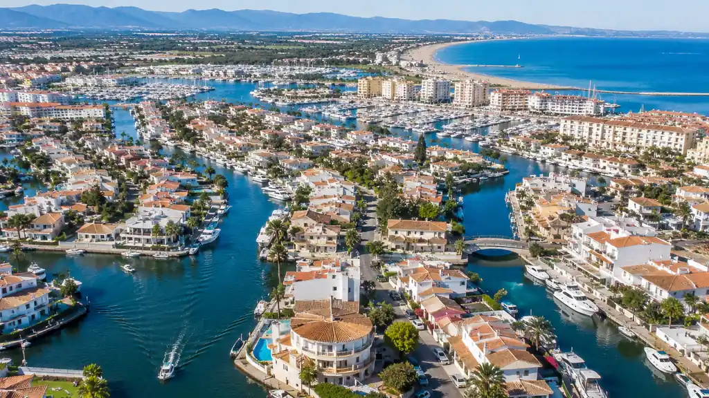 Vue aérienne des canaux d’Empuriabrava avec marina, bateaux, maisons méditerranéennes et plage de la Costa Brava.