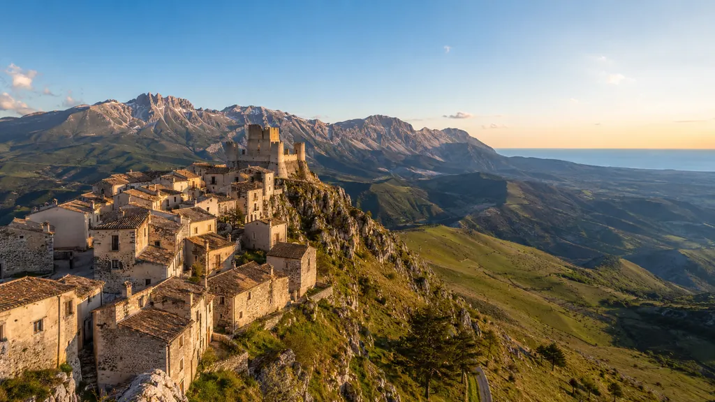 Paysage des Abruzzes avec village médiéval perché, montagnes du Gran Sasso et mer Adriatique au loin.