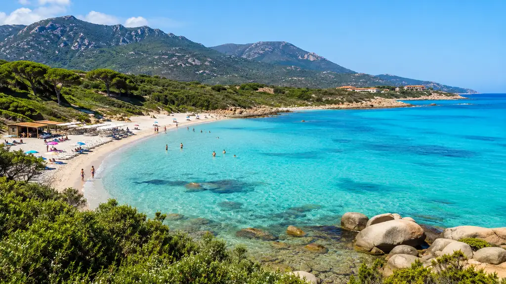 Plage de Bodri en Haute-Corse avec sable blanc, eau turquoise et maquis méditerranéen en arrière-plan.