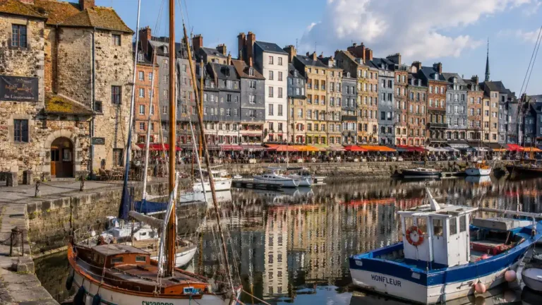Port d’Honfleur avec bateaux amarrés, façades historiques et reflets sur le Vieux Bassin en Normandie.