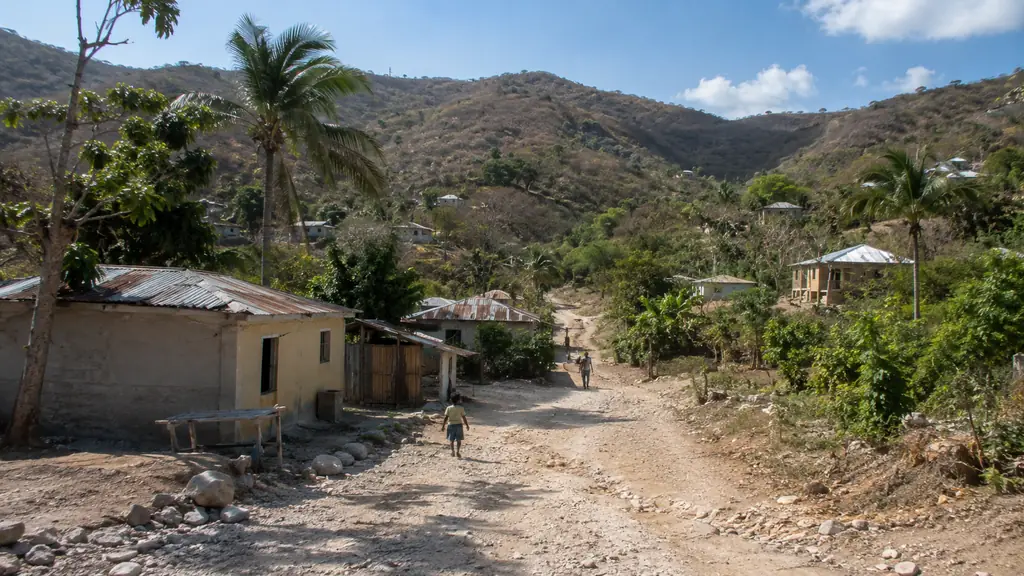 Village rural de Ganere en Haïti avec piste en terre, maisons modestes et collines sèches