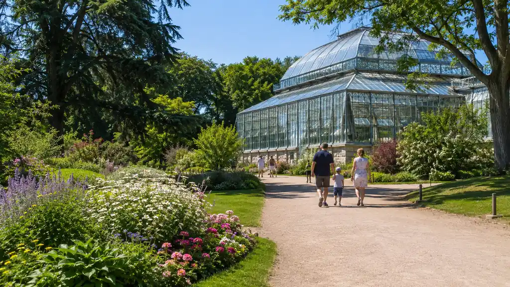 Jardin des Plantes de Rouen avec grande serre, allées fleuries, arbres ombragés et famille en promenade