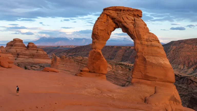 Delicate Arch dans le parc national des Arches en Utah avec roches rouges et montagnes au loin