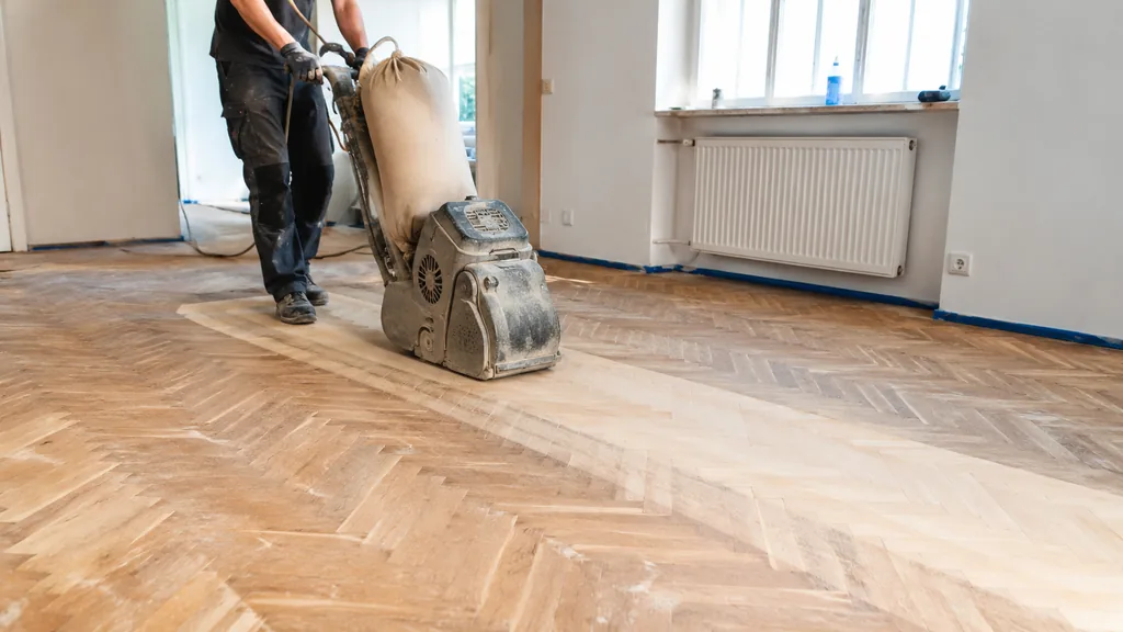 Ponçage parquet avec ponceuse professionnelle sur un sol en bois en cours de rénovation